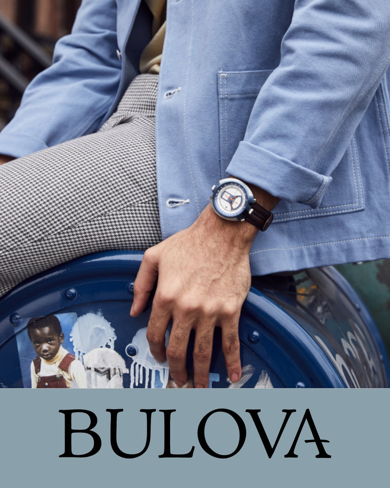 Bulova herreur med blå urkasse og brun rem, vises på herremodels hånd iført lyseblå jakke.
