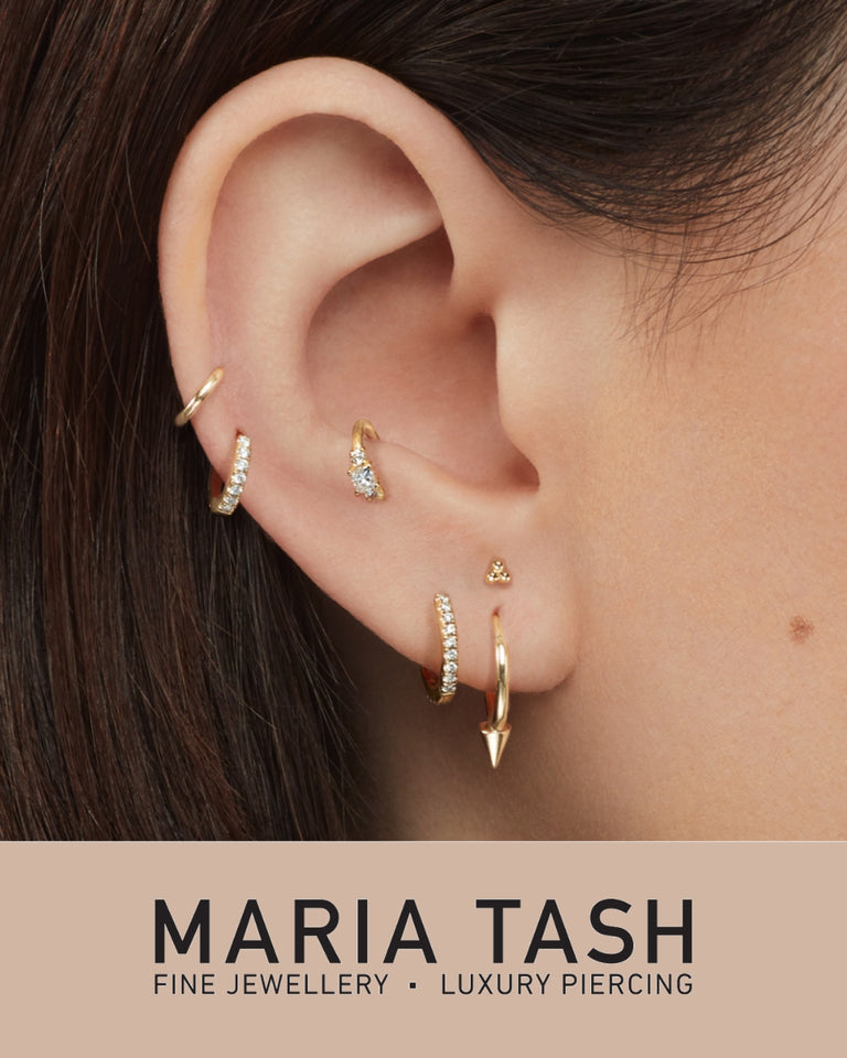 Maria Tash øreringe og piercings i guld med diamanter vist på øre, forside modelbillede.