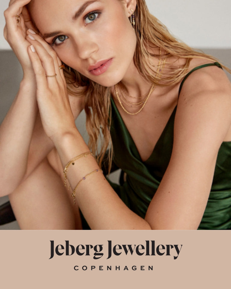 Jeberg Jewellery model i grøn kjole viser armbånd, halskæder og ringe i guld, forsidebillede.