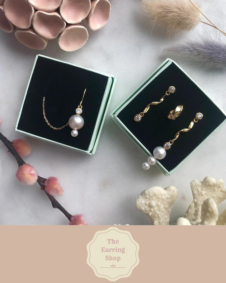 The Earring Shop logo med beige baggrund og elegant indramning, forside af branding.